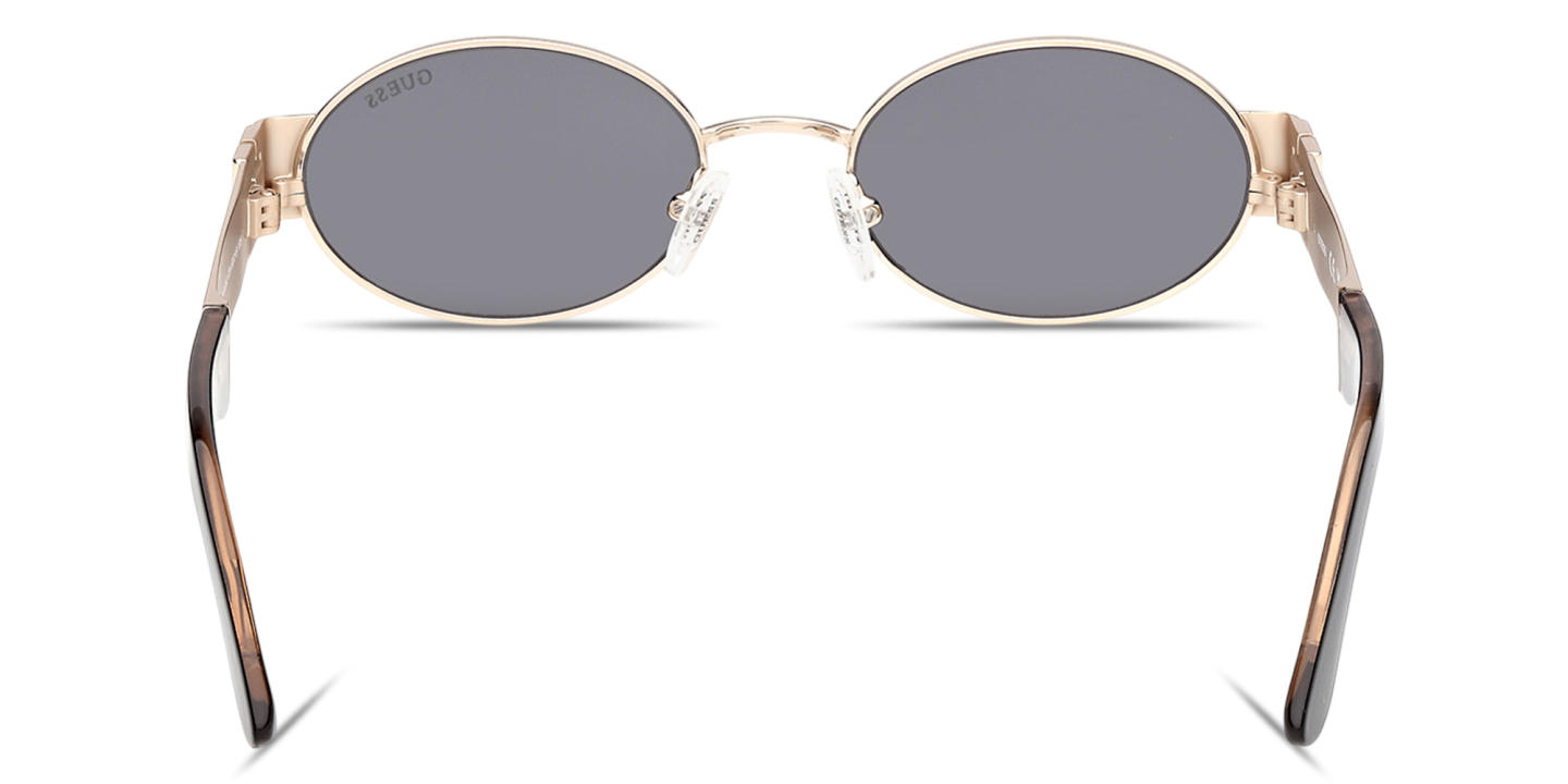 Shop Guess Iris Oval Sunglasses in Gold online.